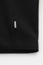 Schwarzer Bouclé-Strick aus reiner Schurwolle mit kleinem Weblabel, Detailansicht der 04651/ A trip in a bag Wolljacke 'Boiled Blouson' schwarz.