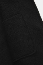 Detailansicht der schwarzen 04651/ A trip in a bag Wolljacke 'Boiled Blouson' Slim Fit mit Bouclé-Strick, Metall-Reißverschluss, Umlegekragen und Raw-Edge-Finish.