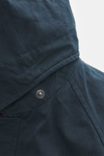 Alt-Tag (124 Zeichen): Nahaufnahme aus seitlicher Perspektive der 04651/ A trip in a bag Wachsjacke 'Sailor' navy/braun mit Kapuze und Druckknopf.
