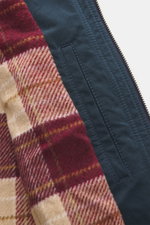 Nahaufnahme der Innenseite der 04651/ A trip in a bag Wachsjacke 'Sailor' navy/braun, zeigt das karierte Flanellfutter und navyblauen Stoff mit Reißverschluss.