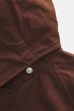 Nahaufnahme der Kapuze der 04651/ A trip in a bag Wachsjacke 'Sailor' braun aus gewachster Baumwolle mit Druckknopf, fotografiert von schräg oben.