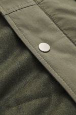 Nahaufnahme von olivgrünem Stoff mit Druckknopf, Detailansicht des 04651/ A trip in a bag Parka 'Winter' oliv, Mix aus Baumwolle und Microfaser, weicher Griff, Oversized Fit, hoch schließender Kragen, praktische Kapuze, robuster Reißverschluss, Windblende