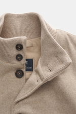 Eddy Monetti Cashmere Daunenblouson 'Teos' beige in Nahaufnahme von oben, zeigt Stehkragen aus Rippstrick, Sechs-Knopf-Leiste, weiche Cashmere-Qualität, leichte Daunenfüllung und glattes Futter.