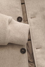 Nahaufnahme des Eddy Monetti Cashmere Daunenblouson 'Teos' beige von vorne, zeigt weiche Cashmere-Qualität, Rippbündchen und Daunenfüllung.