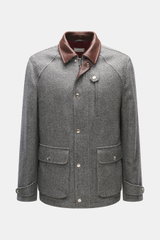 Front view of a Brunello Cucinelli Jacke grau, a slim-fit grey jacket with brown leather collar, chest and front flap pockets, button cuffs, and adjustable waist tabs. Made from a mix of cashmere and virgin wool with a removable Thermore-padded liner for 