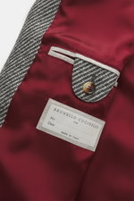 Close-up inside view of the Brunello Cucinelli Jacke grau showing the grey wool-cashmere fabric, red satin lining, buttoned pocket flap, and label.