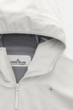 Nahaufnahme der Stone Island Jacke 'Stellina' offwhite aus frontaler Perspektive, hochwertige Microfaser, wind- und wasserabweisend, Regular Fit, Zwei-Wege-Reißverschluss, hochverschließbarer Kragen, praktische Kapuze, 'Stellina'-Stitching auf der Brust.