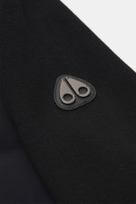 Close-up view of the typical metal logo on the upper arm of the Moose Knuckles Down Blouson 'Kamet Hybrid' black, made of viscose and microfiber with knitted back and sleeves, soft touch, slim fit, robust two-way zipper, high closing ribbed collar, slante