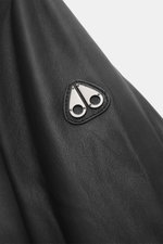 Close-up front-side view of Moose Knuckles Leather blouson 'Toba Bomber' black showing fine lamb leather texture and metal logo on sleeve.  
  
<p>Perfect for urban winter looks: The 'Toba Bomber' blouson from MOOSE KNUCKLES made of fine leather with the 