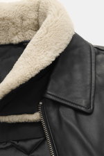 Close-up front-side view of Moose Knuckles Leather blouson 'Toba Bomber' black, showing lambskin collar and smooth black leather with zipper.

<p>Perfect for urban winter looks: The 'Toba Bomber' blouson from MOOSE KNUCKLES made of fine leather with the b