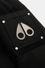 Close-up of the metal logo on the upper arm of the Moose Knuckles Down jacket 'Original 3Q' black, photographed from above. Easily withstands extreme cold up to -30°C with 90/10 down filling, wind- and water-repellent cotton-microfiber mix, detachable hoo