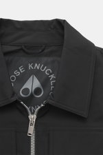 Close-up front view of the Moose Knuckles Jacket 'Jacques' black, featuring high-quality microfiber, smooth feel, slim fit, robust two-way zipper, turn-down collar, patch chest pockets with flap, slanted welt pockets, metal logo on upper arm, cuff sleeves