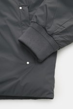 Nahaufnahme der elastischen Ärmelbündchen und Taschenpartie der Moose Knuckles Daunenjacke 'Northdale' dunkelgrau aus Microfaser, wind- und wasserabweisend.