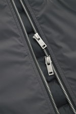 Nahaufnahme des Zwei-Wege-Reißverschlusses der Moose Knuckles Daunenjacke 'Northdale' dunkelgrau aus glatter, wind- und wasserabweisender Microfaser.