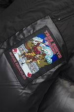 Close-up inside view of Moose Knuckles Down jacket 'Briar 3Q' black showing high-quality microfiber, smooth touch, quilted lining fabric, and detailed patch.