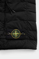 Close-up of the lower section of the black Stone Island Daunenweste 'Seamless Tunnel Nylon Down-TC' showing the compass badge and quilted nylon fabric.

Description: <p>Die Outdoorweste 'Seamless Tunnel Nylon Down-TC' von STONE ISLAND überzeugt mit leicht