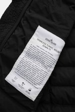 Close-up interior view of the Stone Island Daunenweste 'Seamless Tunnel Nylon Down-TC' schwarz label on black fabric, highlighting fabric research, garment dyeing, and direct feather injection. 

<p>Die Outdoorweste 'Seamless Tunnel Nylon Down-TC' von STO
