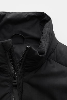 Close-up front view of the black Canada Goose Daunenweste 'Lodge' with a padded stand-up collar and robust two-way zipper, featuring ripstop microfiber fabric, smooth feel, wind- and water-resistant, lightweight down fill, slim fit, tonal web label, side 