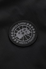 Canada Goose Daunenweste 'Lodge' schwarz close-up showing the tonal Ripstop microfiber fabric and embroidered Arctic Program patch, photographed from above. Die superleichte Daunenweste 'Lodge' von CANADA GOOSE mit hochwertigem Ripstop-Obermaterial lässt 
