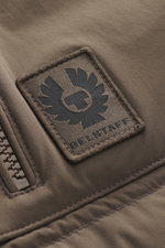 Detailaufnahme der Belstaff Daunenweste 'Chassis' graubraun aus naher Perspektive mit hochwertigem Microfaserstoff, robustem Reißverschluss, BELSTAFF-Weblabel und glattem Griff.