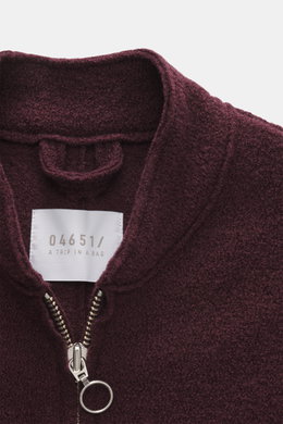 Nahaufnahme aus schräger Perspektive der bordeauxfarbenen 04651/ A trip in a bag Woll-Weste 'Boiled' mit Bouclé-Strick aus reiner Schurwolle, gewalkter Qualität, weichem Griff, Raw-Edge-Finish, Slim Fit, Metall-Reißverschluss, Stehkragen, aufgesetzter Bru