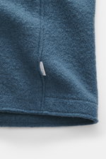 Nahaufnahme von graublauer 04651/ A trip in a bag Woll-Weste 'Boiled' mit Bouclé-Strick, Raw-Edge-Finish und kleinem Weblabel, Detailansicht.