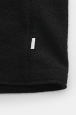 Schwarzes Detailfoto der 04651/ A trip in a bag Woll-Weste 'Boiled' schwarz mit Bouclé-Strick aus reiner Schurwolle, Raw-Edge-Finish, kleinem Weblabel.