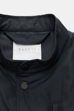 Nahaufnahme des Stehkragens und der Fünf-Knopf-Leiste der 04651/ A trip in a bag Outdoorweste 'Padded Nylon' navy aus glatter Microfaser.