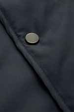 Nahaufnahme eines schwarzen Metallknopfs auf navyblauem Microfaserstoff der 04651/ A trip in a bag Outdoorweste 'Padded Nylon' navy mit glattem Griff und Slim Fit.