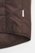 Nahaufnahme der dunkelbraunen 04651/ A trip in a bag Outdoorweste 'Padded Nylon', Detail des hochwertigen, glatten Mikrofaserstoffs, aus frontaler Perspektive.