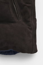Nahaufnahme der Eddy Monetti Veloursleder-Daunenweste dunkelbraun von unten rechts fotografiert mit softem Veloursleder, weichem Griff, wärmender Daunenfüllung, Slim Fit, Zwei-Wege-Reißverschluss, Stehkragen, Zipper-Fronttaschen, geschmeidigem Futterstoff