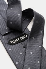 Close-up of a Tom Ford Seidenkrawatte, dark grey with dots, silk, subtle shine, logo stitching, made in Italy.