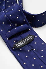 Nahaufnahme der Tom Ford Seidenkrawatte dunkelblau/creme gepunktet, aus reiner Seide mit dezentem Glanz, Logo-Stitching, monochromem Futterstoff, Breite 8 cm, made in Italy, zeitloser Stil, fotografiert von oben.