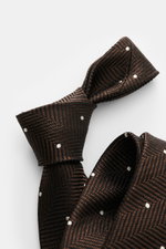 Tom Ford Seidenkrawatte dunkelbraun/schwarz/creme gemustert, Nahaufnahme von oben, Fischgratmuster mit Punkten, reine Seide, dezenter Glanz, Logo-Stitching, made in Italy, Breite 8 cm.