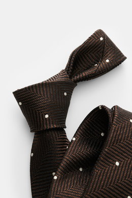 Tom Ford Seidenkrawatte dunkelbraun/schwarz/creme gemustert, Nahaufnahme von oben, Fischgratmuster mit Punkten, reine Seide, dezenter Glanz, Logo-Stitching, made in Italy, Breite 8 cm.