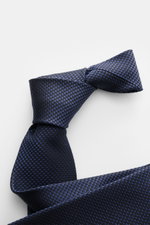 Tom Ford Seidenkrawatte dunkelblau/schwarz gemustert, Hahnentrittmuster, dezenter Glanz, reine Seide, Logo-Stitching, Nahaufnahme von schräger Perspektive.