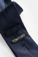 Tom Ford Seidenkrawatte dunkelblau/schwarz gemustert mit zeitlosem Hahnentrittmuster, Logo-Stitching, reine Seide, Detailaufnahme von schräger Perspektive.