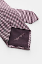 Nahaufnahme der Tom Ford Seidenkrawatte rosé/schwarz gemustert mit zeitlosem Hahnentrittmuster, Logo-Stitching und dezentem Glanz, fotografiert von oben.