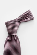 Tom Ford Seidenkrawatte rosé/schwarz gemustert mit zeitlosem Hahnentrittmuster, dezenter Glanz, reine Seide, Logo-Stitching, Nahaufnahme von oben.