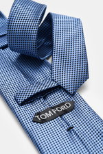 Tom Ford Seidenkrawatte rauchblau/schwarz gemustert, Nahaufnahme seitlich, reine Seide, dezenter Glanz, Hahnentritt, Logo-Stitching, made in Italy.