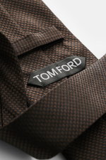 Tom Ford Seidenkrawatte dunkelbraun/schwarz gemustert, Hahnentritt, dezenter Glanz, Logo-Stitching, reine Seide, Detailfoto aus schräger Nahaufnahme.