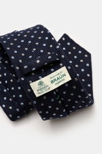 Nahaufnahme der Borrelli Krawatte navy/hellblau/creme gepunktet, handgefertigt in Italien aus Seide und Schurwolle mit deutlicher Webstruktur und tonalem Futterstoff, fotografiert von oben schräg.