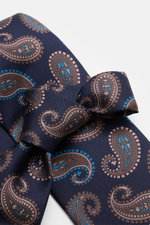 Nahaufnahme der handgefertigten Borrelli Seidenkrawatte navy/blau/taupe gemustert mit grafischem Muster, dezentem Glanz, tonalem Futterstoff, Breite 8 cm, Made in Italy, seitliche Perspektive.