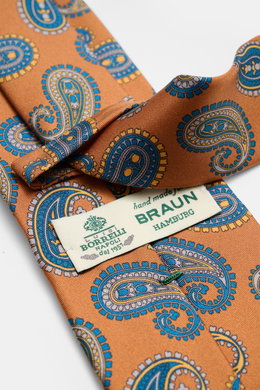 Blick von schräg oben auf die Borrelli Seidenkrawatte orange/dunkelblau/rauchblau gemustert mit grafischem Muster, handgefertigt aus reiner Seide, dezentem Glanz, tonalem Futterstoff, Made in Italy, Breite 8 cm.
