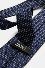 Nahaufnahme der Zegna Krawatte navy/creme/schwarz gemustert mit grafischem Muster, dezentem Glanz, aus reiner Seide, Made in Italy, Breite ca. 8 cm, liegend fotografiert.