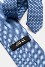 Zegna Seidenkrawatte hellblau/dunkelblau gemustert, Nahaufnahme von oben, reine Seide, dezenter Glanz, grafisches Webmuster, kontrastfarbener Futterstoff, Made in Italy, Breite ca. 8 cm.
