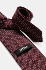 Zegna Silk tie burgundy/black/cream patterned, photographed from a close-up side angle, showing pure silk, subtle shine, graphic pattern, Made in Italy, width approx. 8 cm.