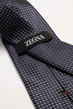 Nahaufnahme der Zegna Krawatte navy/hellgrau/schwarz gemustert mit grafischem Muster, dezentem Glanz, reine Seide, Made in Italy, Breite ca. 8 cm, von oben fotografiert.
