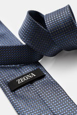 Zegna Silk tie smoke blue/black/cream patterned shown from a close-up side angle, featuring pure silk, subtle shine, graphic pattern, Made in Italy, width approx. 8 cm.