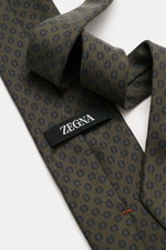 Zegna Seidenkrawatte dunkelgrün/navy gemustert, Nahaufnahme von oben, reine Seide, dezenter Glanz, grafisches Webmuster, kontrastfarbener Futterstoff, Made in Italy, Breite ca. 8 cm.